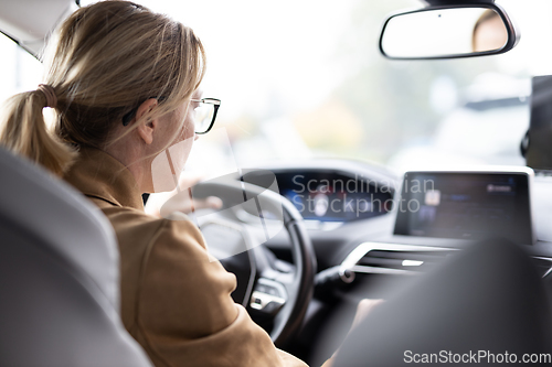 Image of Business woman driving a car to work. Female driver steering car on the road