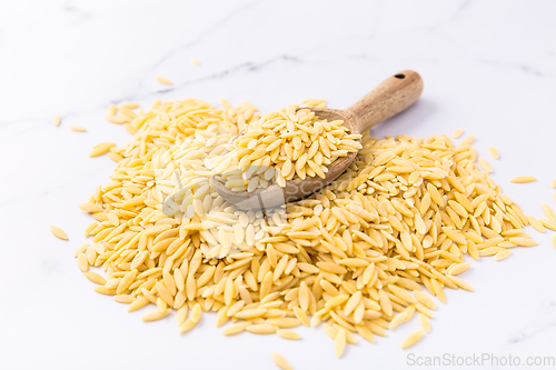 Image of Raw orzo pasta (risoni) with wooden spoon