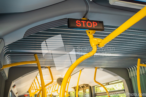 Image of Stop sign in city bus. Empty bus interior. Bus with blue seats and yellow handrails