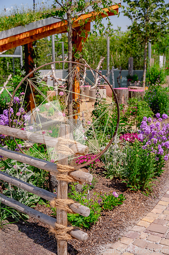 Image of Detail of natural garden fence made of wooden posts and ropes with native plants and patio