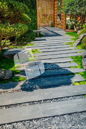 Image of Detail of slate path with bark mulch and native plants in Japanese garden. Landscaping and gardening concept.