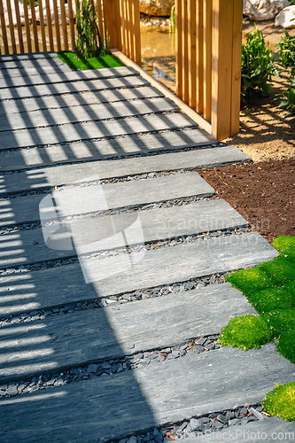 Image of Detail of slate path with bark mulch and native plants in Japanese garden. Landscaping and gardening concept.