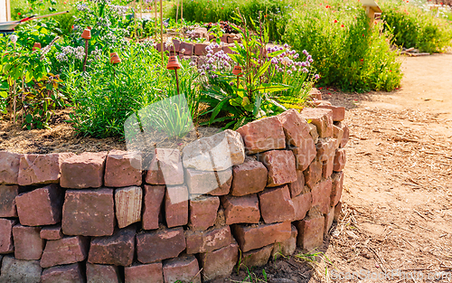 Image of Herb spiral made of bricks for a small garden with sorrel, garlic mustard and chives