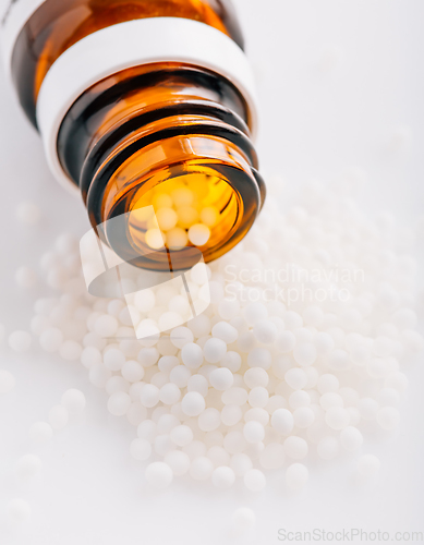 Image of Homeopathic globules and glass bottle. Homeopathy, alternative medicine.