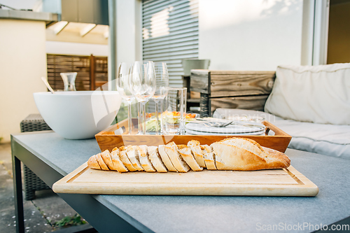Image of Freshly baked baguette with healthy snack and glasses on terrace or patio