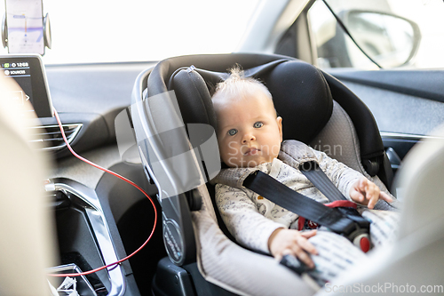 Image of Cute little baby boy strapped into infant car seat in passenger compartment during car drive.