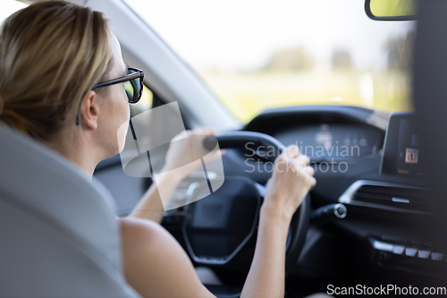 Image of Business woman driving a car to work. Female driver steering car on the road