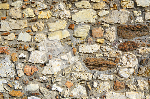 Image of Old wall texture of various stones lit by the sun