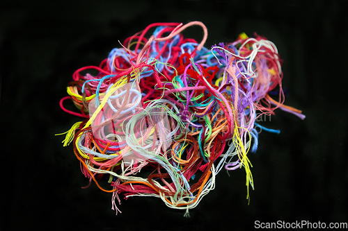 Image of Ball of multicolored tangled threads for needlework on black bac