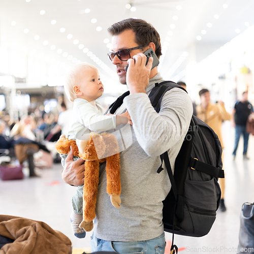 Image of Father traveling with child, holding his infant baby boy at airport terminal waiting to board a plane. Travel with kids concept.