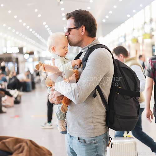 Image of Father traveling with child, holding his infant baby boy at airport terminal waiting to board a plane. Travel with kids concept.