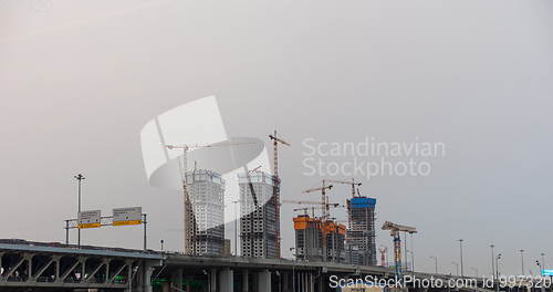 Image of Many of cranes. Tower cranes against blue sky, with clouds