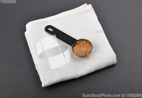 Image of Carob powder in measuring spoon on shale