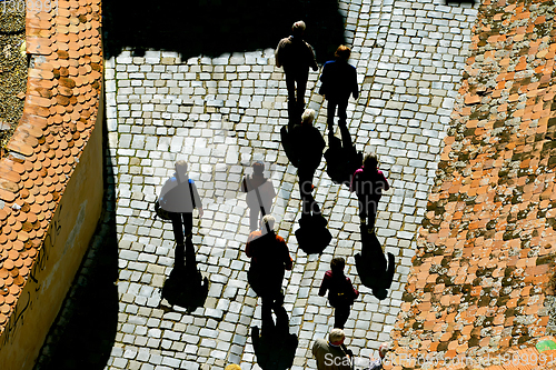 Image of people walking by cobblestone street 