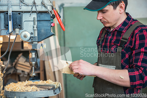 Image of Carpenters with electric drill machine drilling wooden board