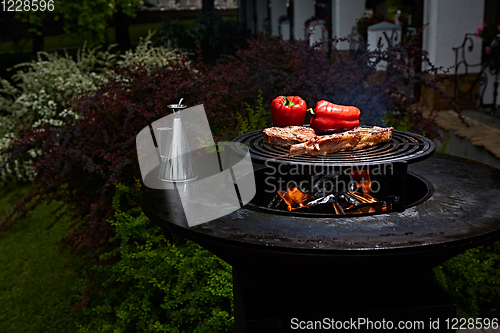 Image of Tomahawk rib beef steak and T-bone on hot black grill.