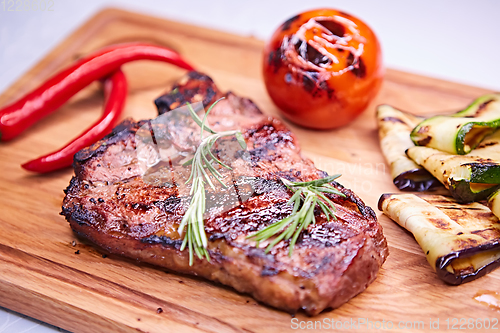 Image of Grilled T-Bone Steak on serving board on wooden background