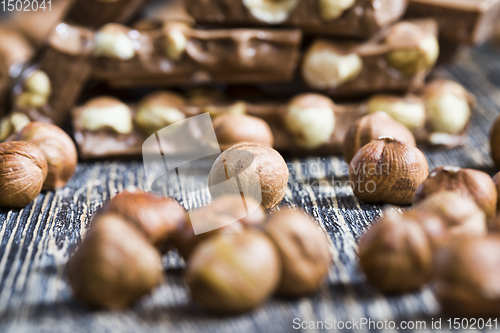 Image of bitter real chocolate, photographed close-up with whole hazelnuts inside and next to a bar of broken chocolate