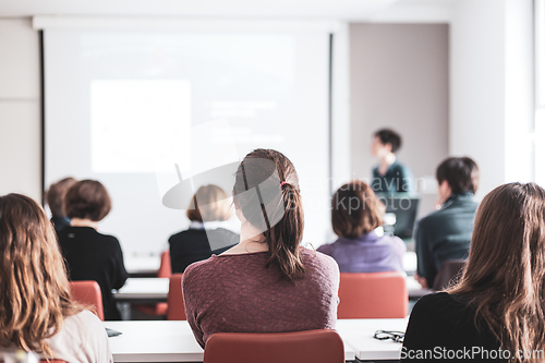 Image of Female speaker giving presentation in lecture hall at university workshop . Participants listening to lecture and making notes. Scientific conference event