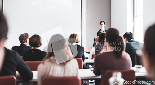 Image of Female speaker giving presentation in lecture hall at university workshop . Participants listening to lecture and making notes. Scientific conference event