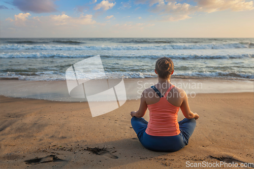 Image of Woman doing yoga oudoors at beach - Padmasana lotus pose