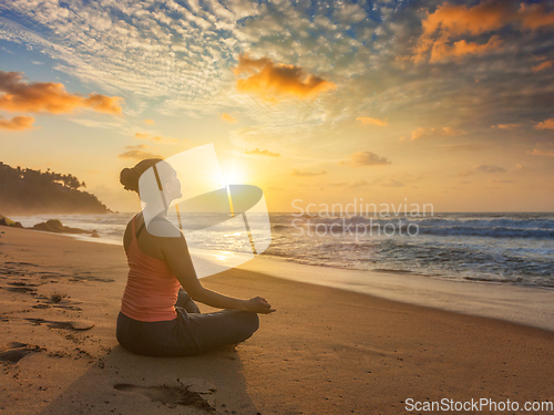 Image of Woman doing yoga oudoors at beach - Padmasana lotus pose