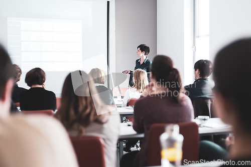 Image of Female speaker giving presentation in lecture hall at university workshop . Participants listening to lecture and making notes. Scientific conference event