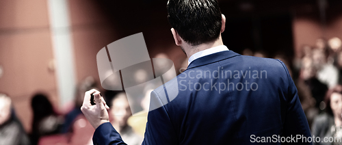 Image of Rear view of speaker giving a talk on corporate Business Conference. Audience at the conference hall. Business and Entrepreneurship event. Panoramic composition