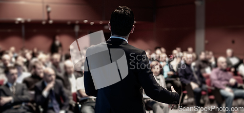 Image of Public speaker giving talk at business event.