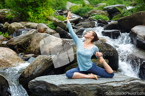 Image of Woman doing yoga outdoors at tropical waterfall