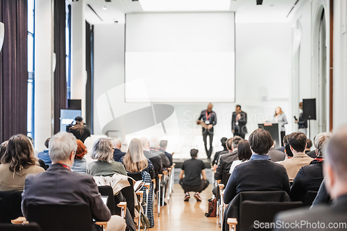 Image of Business team leader receiving award prize at best business project competition event. Business and entrepreneurship award ceremony theme. Focus on unrecognizable people in audience.