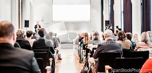 Image of Speaker giving a talk in conference hall at business event. Rear view of unrecognizable people in audience at the conference hall. Business and entrepreneurship concept.