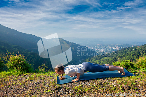 Image of Woman practices yoga asana Chaturanga Dandasana
