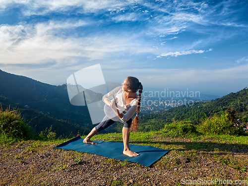 Image of Woman practices yoga asana Utthita Parsvakonasana