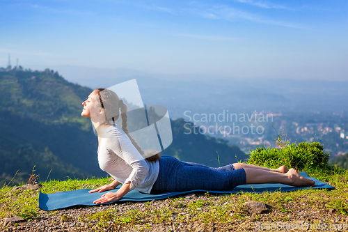 Image of Woman practices yoga asana bhujangasana cobra pose