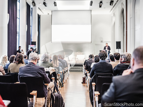 Image of Speaker giving a talk in conference hall at business event. Rear view of unrecognizable people in audience at the conference hall. Business and entrepreneurship concept.