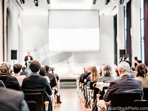 Image of Speaker giving a talk in conference hall at business event. Rear view of unrecognizable people in audience at the conference hall. Business and entrepreneurship concept.