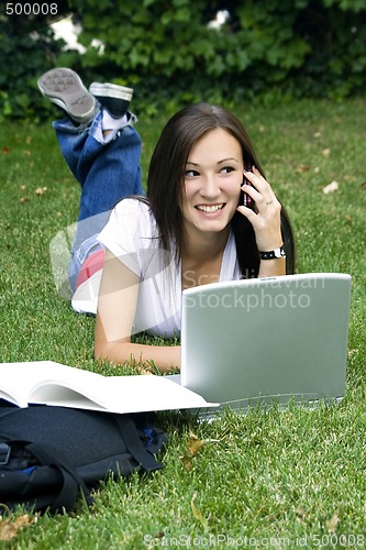 Image of Cute teen girl laying down on the grass studying
