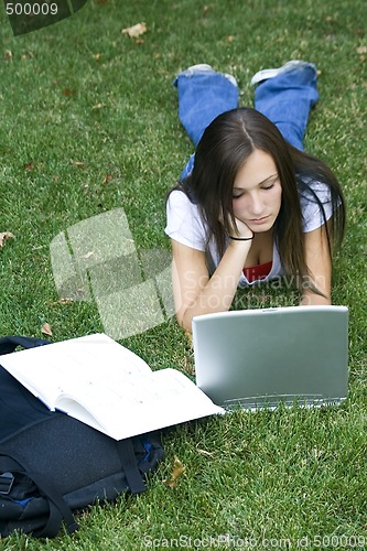 Image of Cute teen girl laying down on the grass studying