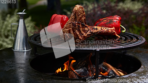 Image of Tomahawk rib beef steak and T-bone on hot black grill.