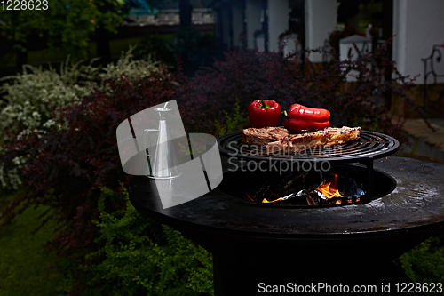 Image of Tomahawk rib beef steak and T-bone on hot black grill.