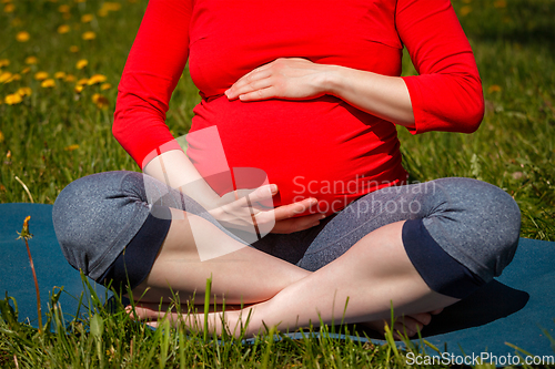 Image of Pregnant woman doing asana Sukhasana outdoors