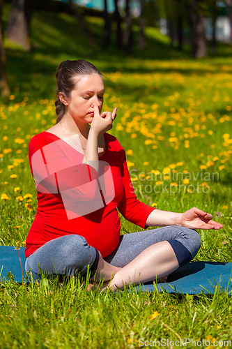 Image of Pregnant woman doing pranayama breath exercise outdoors