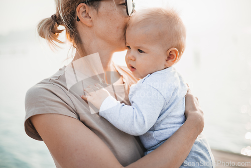 Image of Tender woman caressing her little baby boy infant child outdoors. Mother's unconditional love for her child