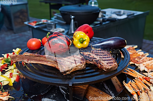 Image of Tomahawk rib beef steak and T-bone on hot black grill.