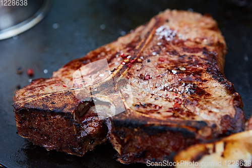 Image of Grilled T-Bone Steak on serving board on wooden background