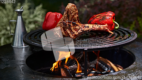 Image of Tomahawk rib beef steak and T-bone on hot black grill.