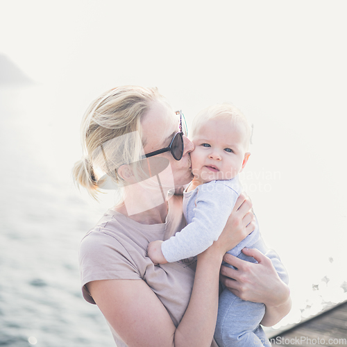 Image of Tender woman caressing her little baby boy infant child outdoors. Mother's unconditional love for her child