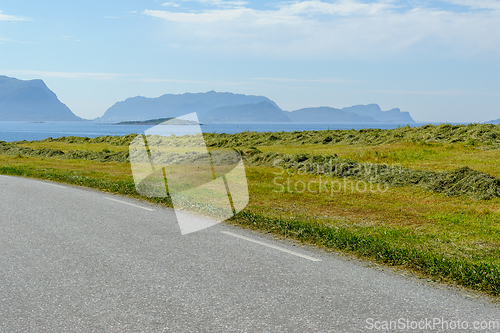 Image of freshly cut grass to dry by the road and sea and islands on the 