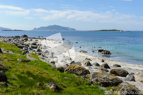 Image of beach with rocks and grass on the coast with islands in the dist